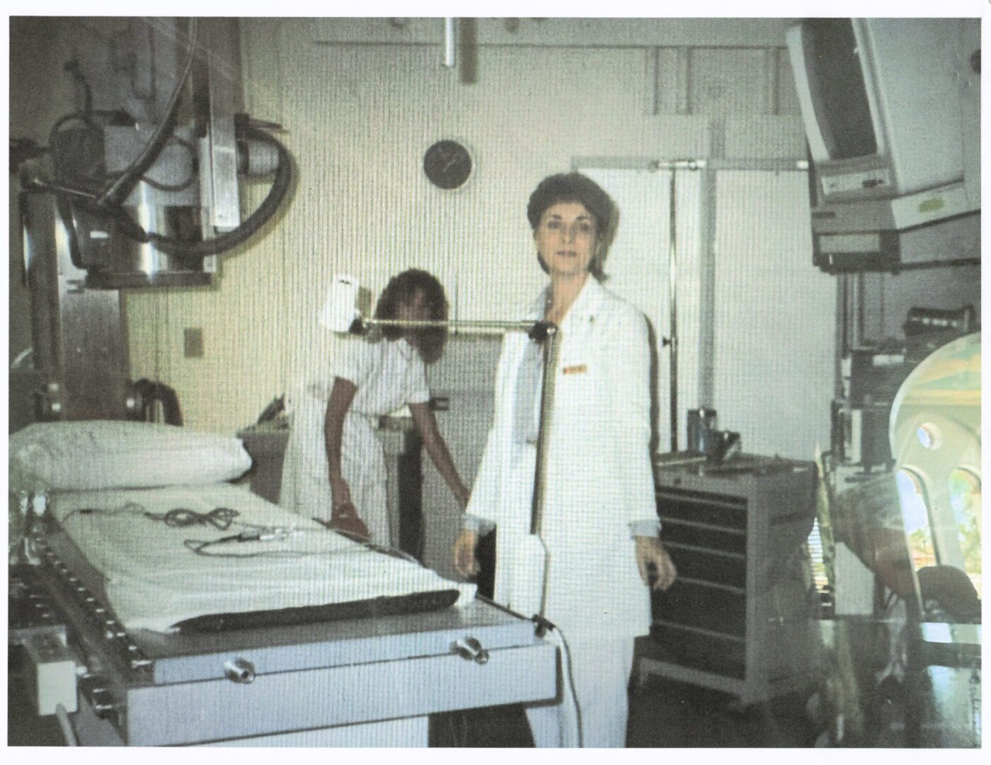 Two women in a hospital room, one in a white uniform.